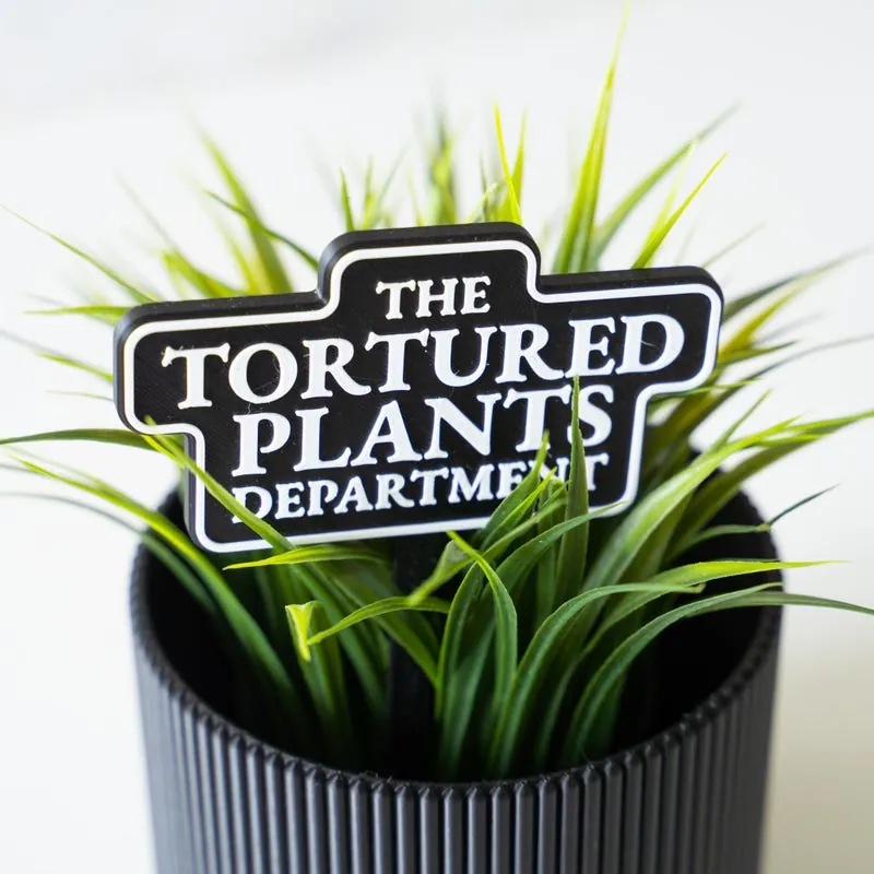 Tortured Plants Department garden stake in a potted grass